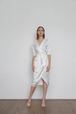 Stüdyo fotoğrafları, zarif beyaz ipek saten elbise giyen çekici genç bir kadın..