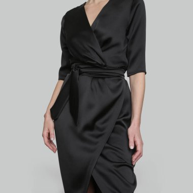 Stüdyo fotoğrafları, zarif siyah ipek saten elbise giyen çekici genç bir kadın..