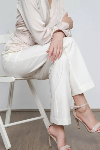 Serie of studio photos of young female model wearing simple beautiful outfit, silk satin wrap blouse and straight leg trousers