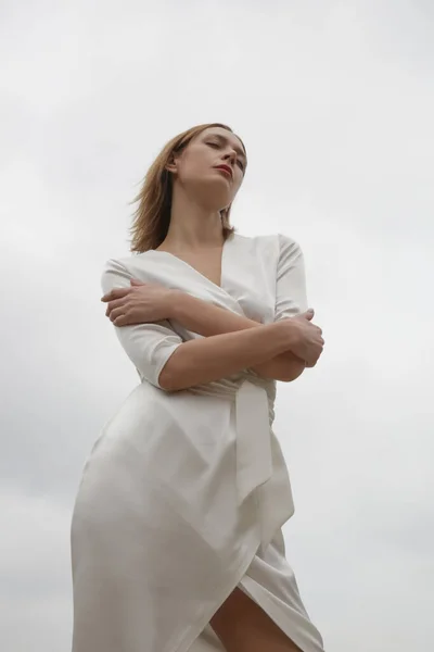 セリエのスタジオ写真の魅力的な若い女性のエレガントな白い絹のサテンのドレスを着て — ストック写真