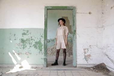 Terk edilmiş binada bej elbiseli kadın modelin ciddi fotoğrafları.