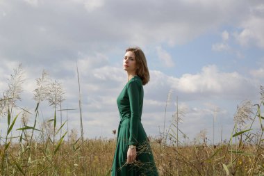 Serie of photos of female model in green dress posing on meadow. Outdoor portrait with natural light. clipart