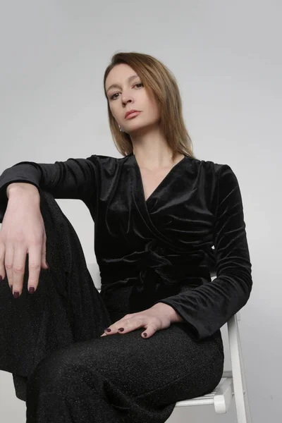 輝く黒のジャンプスーツを着た女性モデルのスタジオ写真のセリエ 大晦日パーティーのためのシンプルで効果的な衣装 ホリデーシーズン服 — ストック写真