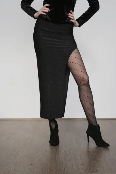 女模特穿着闪亮的黑色紧身裙 有深深的缝隙 心灵深处印着半透明的紧身衣 简单而有效的节日派对服装的摄影棚照片系列 — 图库照片