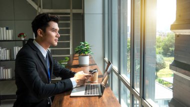 Kahve dükkanında dizüstü bilgisayarla çalışan profesyonel iş adamı tablet ve not defteri kullanarak bilgi analiz ediyor.