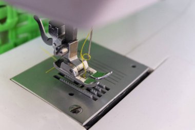 Dikiş makinesi iğnesi sarı iplikle çalışmak için bekliyor.