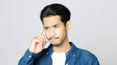 Asyalı bir gencin ciddi düşüncelerini kapatıyoruz. Gri arka planda fotokopi için alan ararken Asyalı adamın portresi yüz ifadesini gösteriyor.  