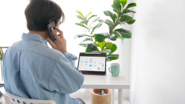 Ofiste mobil uygulama geliştirme prototipi için dijital tabletle çalışırken telefonla konuşan adam