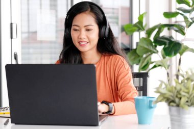 Evde çalışan Asyalı bir kadın dizüstü bilgisayarla evde çalışıyor, Asyalı bir kadın internetten alışveriş yapıyor, internetten öğrenen mutlu bir kız, online eğitim alıyor, ticaret yapıyor.