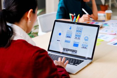 Web sitesi tasarımcısı, Yaratıcı Planlama Telefon Uygulaması Geliştirme şablonu yerleşim şeması kablo şeması tasarımı, Kullanıcı deneyimi konsepti, Ofiste akıllı telefon uygulaması üzerinde çalışan Asyalı genç kadın UX tasarımcısı