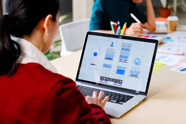 Web sitesi tasarımcısı, Yaratıcı Planlama Telefon Uygulaması Geliştirme şablonu yerleşim şeması kablo şeması tasarımı, Kullanıcı deneyimi konsepti, Ofiste akıllı telefon uygulaması üzerinde çalışan Asyalı genç kadın UX tasarımcısı