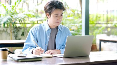 Çevrimiçi eğitim öğrenimi, evden çalışma, dizüstü bilgisayar kullanırken el yazısı, yetişkin erkek öğrenci çevrimiçi kursu  