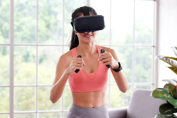 Asian woman virtual reality headset while exercise at home, Healthy asia girl wearing vr glasses for interactive exercise, e sport, Female and wearable technology