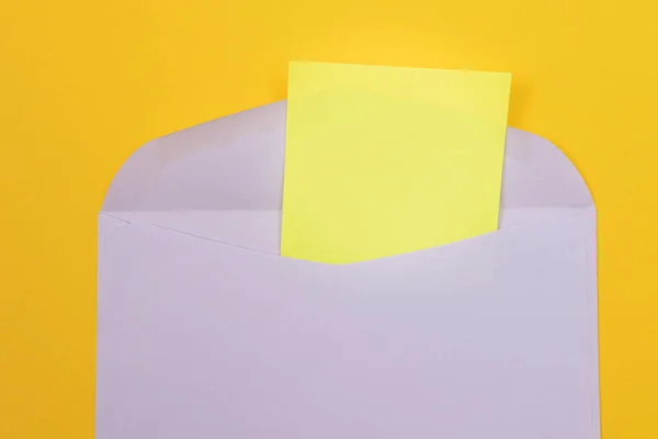 Envelope violeta com folha de papel amarelo em branco dentro — Fotografia de Stock