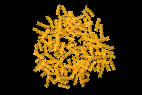 A Heap of Uncooked Fusilli Pasta Scattered on Black Table — Stock Photo, Image