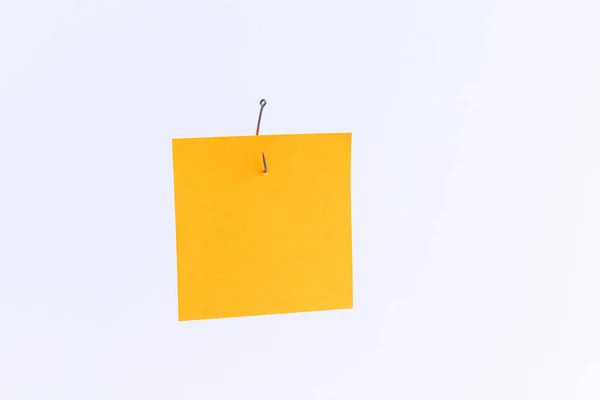 Burla de un papel de memorándum naranja en blanco con espacio de copia colgando de un gancho de pesca —  Fotos de Stock
