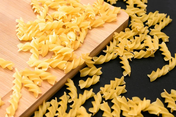 Ungekochte Fusilli-Pasta auf Holzbrettern verstreut — Stockfoto