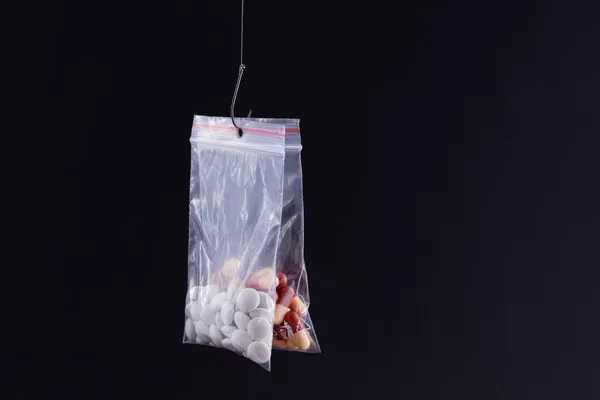 釣針の上に小さなジップロックバッグにぶら下がっている色の丸薬や錠剤 — ストック写真