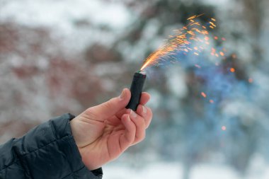 Bir elde yanan havai fişek. Petard 'ın kıvılcımları ve dumanı