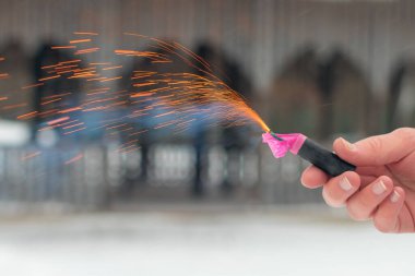Bir elde yanan havai fişek. Petard 'ın kıvılcımları ve dumanı
