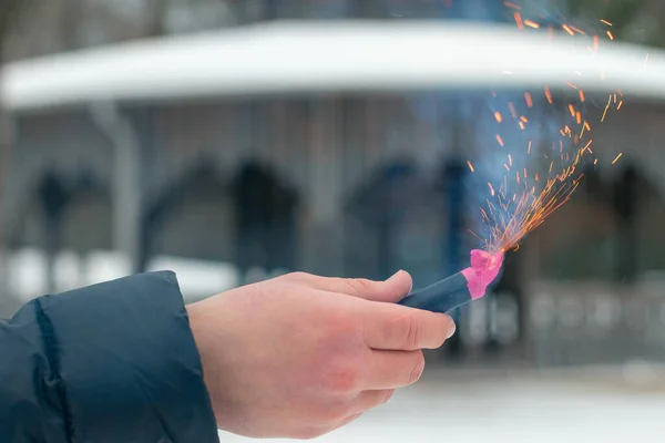 Bir elde yanan havai fişek. Petard 'ın kıvılcımları ve dumanı