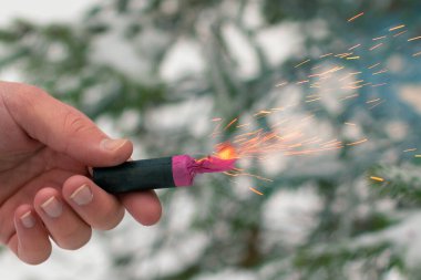Bir elde yanan havai fişek. Petard 'ın kıvılcımları ve dumanı