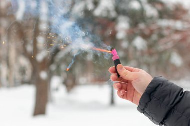 Bir elde yanan havai fişek. Petard 'ın kıvılcımları ve dumanı
