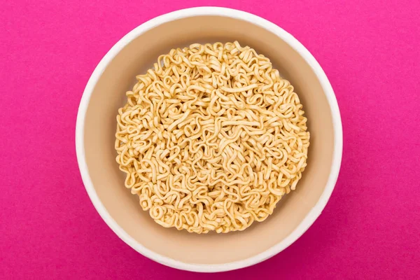 Opened Package with Uncooked Instant Noodles on Pink Background