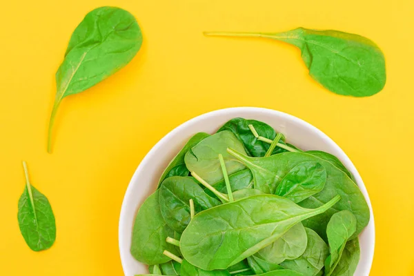Fresh Baby Spinach Leaves in White Bowl on Yellow Background — Stock Photo, Image
