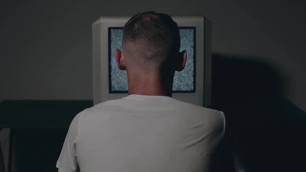 Zombified Man fehér pólóban ül szemben a régi ezüst TV — Stock videók