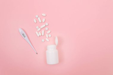 Pembe Arkaplanda Elektronik Termometresi olan Beyaz Haplar veya Tabletler