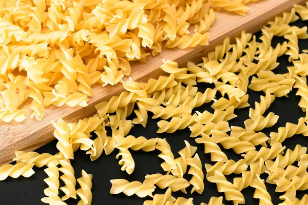 Ungekochte Fusilli-Pasta auf Holzbrettern verstreut — Stockfoto