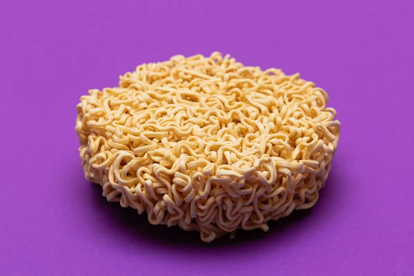 Uncooked Instant Noodles on Violet Background