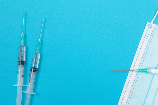 Syringe with Medical Mask on Blue Table - Flat Lay — Stock Photo, Image