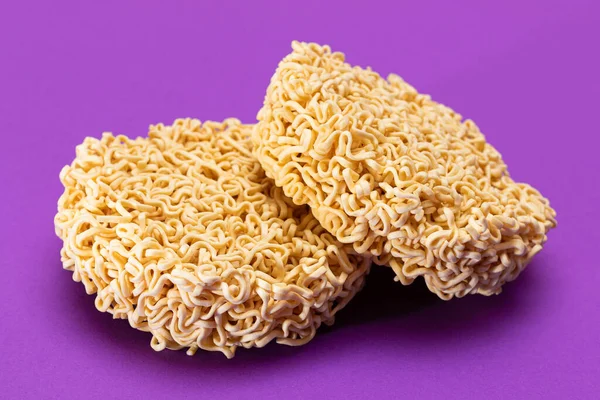 Uncooked Instant Noodles on Violet Background