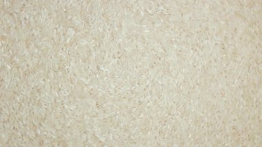 Kurutulmamış beyaz pirinç arka planı yavaşça sağa doğru dönüyor. Çiğ Uzun Taneli Pirinç. Asya mutfağı ve kültürü. Sağlıklı beslenme malzemeleri. Diyet Yemekler