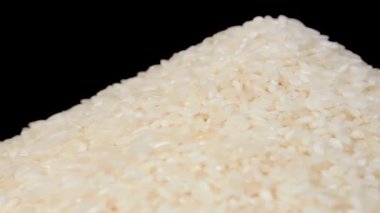 Dry Uncooked White Rice Heap on White Plate Rotating against Black Background. A Pile of Raw Long Grain Rice. Asian Cuisine and Culture. Healthy Eating Ingredients. Diet Food