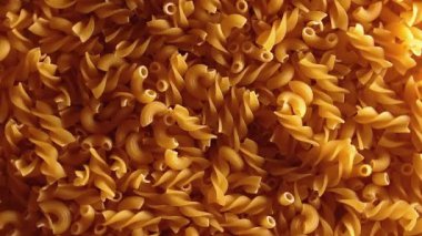 Uncooked Fusilli and Chifferi Rigati Pasta - Top View, Low Key Light. Fat and Unhealthy Food. Classic Dry Macaroni, Slowly Rotating Background. Raw Different Macaroni Pasta Texture - Rotate Right