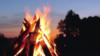 Blue Sky 'a karşı Yaz Gecesinde Büyük Yanan Kamp Ateşi. Ateşe odun. Uçan Kıvılcım. Seyahat ve Turizm Konsepti. Dev Alevli Şenlik Ateşi - Statik Çekim, Yavaş Hareket