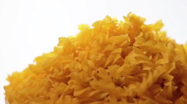 Pişmemiş Fusilli Pasta Yığını Beyaz Arkaplan 'a karşı dönüyor. Şişman ve Sağlıksız Yemek. Kuru Spiral makarna. İtalyan Kültür ve Mutfağı. Çiğ Altın Makarna