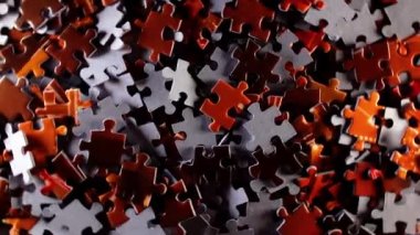 Background of Colored Puzzle Pieces that Rotating Clockwise - Top View. Texture of Incomplete Red and Grey Jigsaw Puzzle with Low Key Light - Right Rotation