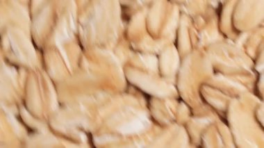 Oat Flakes Background Rotating Counter-Clockwise - Top View, Close-Up. Scattered Dry Oat Flakes. Healthy Breakfast and Diet Eating Ingredients - Angular Rotation Left