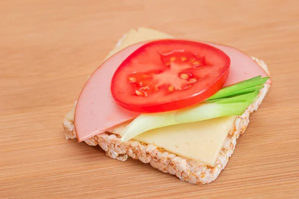 Rice Cake Sandwich with Tomato, Sausage, Green Onions and Cheese on Wooden Cutting Board. Easy Breakfast. Diet Food. Quick and Healthy Sandwiches. Crispbread with Tasty Filling. Healthy Dietary Snack