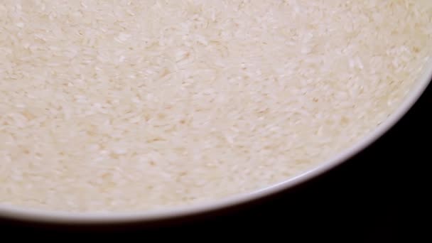 Сухой Сырой Белый Рис Белой Пластине Вращающийся Черном Фоне Рассеянный — стоковое видео