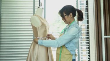 Asyalı kadın terzi moda tasarımcısı galeride manken boyutunda. Terzilik ve moda kavramı