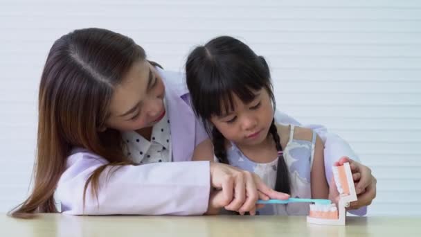 Asiatische Zahnärztin Unterrichtet Süßes Kleines Mädchen Beim Zähneputzen Mit Zahnbürste — Stockvideo