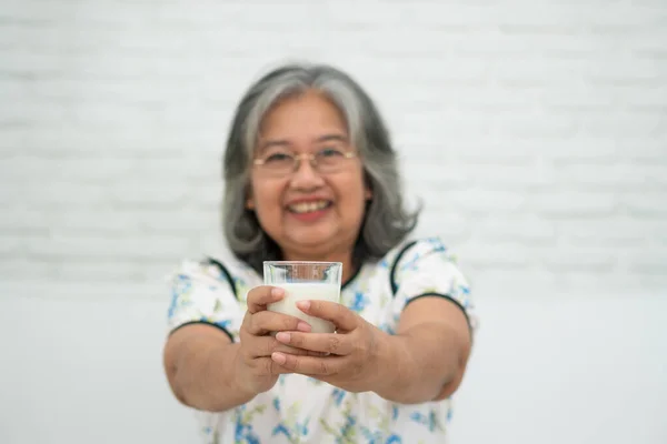 Asiática Senior Mujer Sosteniendo Leche Vidrio Mientras Relaja Sofá Sala — Foto de Stock
