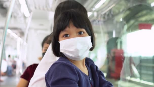 携带外科口罩的小女孩在公共交通 天窗列车或地铁 中面临流感和病毒的保护 新的正常生活概念 利用公共交通工具上学 — 图库视频影像
