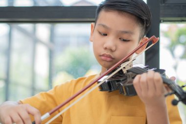 Evde keman çalan ve keman çalan küçük bir Asyalı çocuk, müzik eğitimi konsepti, ilham, gençlik sanat okulu öğrencisi.