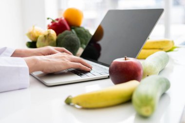 Asyalı gülümseyen kadın beslenme uzmanının portresi hasta ya da kilo verme tavsiyesi için dengeli bir diyet planı için dizüstü bilgisayarda daktilo ediyor. Sağlıklı yaşam biçimi, sağlıklı yemek, diyet